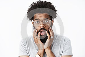 Close-up shot of concerned and worried adult african american bearded guy with afro hairstyle open mouth shook and
