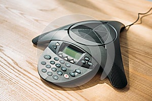 close-up shot of conference phone on wooden table