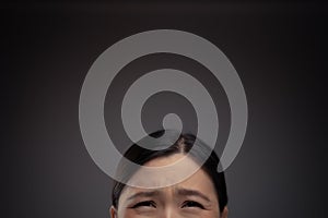 Close up shot of confused Asian woman look up with copy space