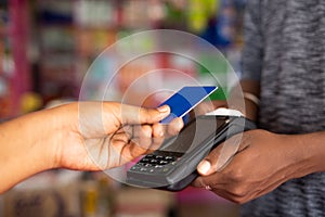 Close up shot of customer paying money by tapping credit card to swiping machine at grocery shop - concept of digital