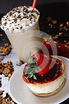 Close up shot of delicious milkshake with whipped cream on top and a strawberry cake