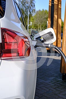 Close-up shot of an electric car charging at a recharging station, with the wires connected