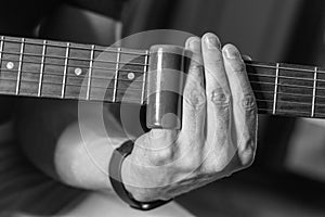 Close-up shot of an electric guitar player performing with slider technique, grayscale