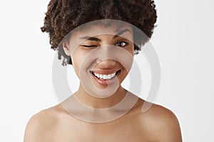 Close-up shot of emotive happy and friendly-looking attractive dark-skinned model with afro hairstyle posing naked