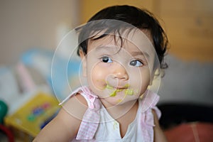 Close up shot of face Asian baby with mouth soiled food after eating, looking out