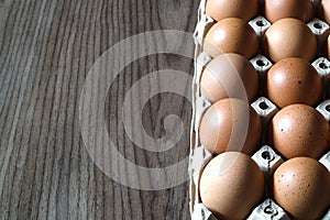 Close-up shot of farm-fresh eggs in a box placed on a wooden table.