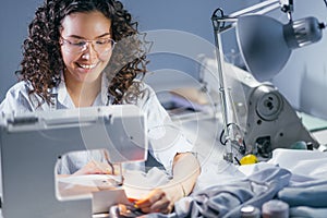 Close-up shot of femaile tailor mending fabric on sewing machine indoors