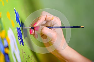 Close-up Shot of Female Artist Hand, Holding Paint Brush and Drawing Oil Painting. Contemporary Painter Creating Modern