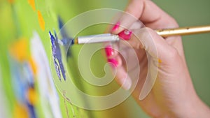 Close-up Shot of Female Artist Hand, Holding Paint Brush and Drawing Oil Painting. Contemporary Painter Creating Modern