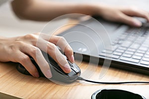 Close-up shot of female hand holding mouse and working with desktop computer