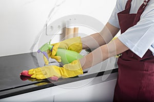 Close up shot of female hands holding bottle spray and rag for cleaning the stove