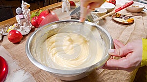 Close-up shot of female hands preparing dough for delicious muffins using a whisk in the kitchen