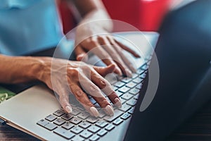 Close-up shot of female hands typing on laptop keyboard