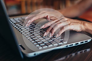 Close-up shot of female hands typing on laptop keyboard