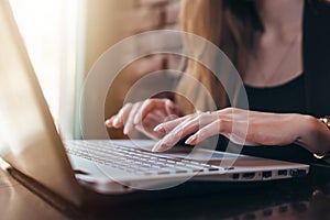 Close-up shot of female hands typing on laptop keyboard