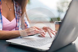 Close up shot of female hands typing on a laptop keyboard. Young woman studying and working in the park