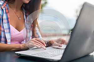 Close up shot of female hands typing on a laptop keyboard. Young woman studying and working in the park