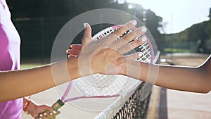 Close up shot of female tennis players shaking hands over the tennis court net.