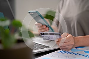 Close up shot of females hands holding credit card typing message on smart phone for shopping online