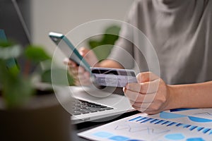 Close up shot of females hands holding credit card typing message on smart phone for shopping online