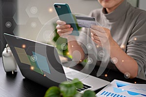 Close up shot of females hands holding credit card typing message on smart phone with technology icons for shopping online