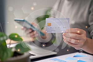 Close up shot of females hands holding credit card typing message on smart phone with technology icons for shopping online