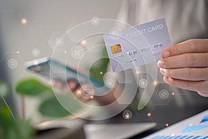 Close up shot of females hands holding credit card typing message on smart phone with technology icons for shopping online