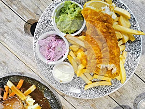 Close up shot of fish and chip food with side garnishes. Fast cooked food