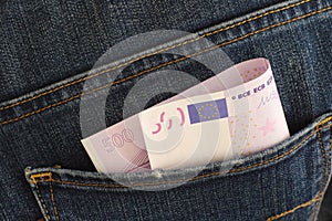 A close-up shot of a five hundred euro banknote in the back pocket of blue jeans