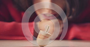 Close up shot of a girl spinning a Hanukka dreidel on the floor