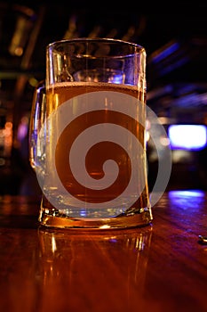 Close up shot of glass of beer on a blurry pub background. Selective focus