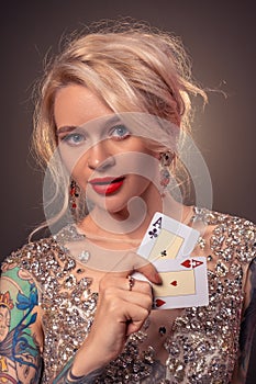 Blonde woman with a beautiful hairstyle and perfect make-up is posing with playing cards in her hands. Casino, poker.