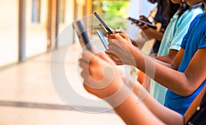 Close up shot, group of children hands busy using smartphone at school corridor - concept of social media, playing games