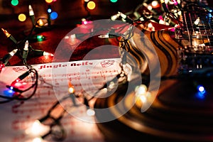 Close up shot of Guitar Music for the holiday season.  Jingle Bells sheet music and Christmas lights accompany a beautiful