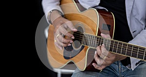 Close up shot of guitarist playing acoustic guitar on black background with copy space for folk music and unplugged performance