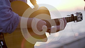 Close up shot of a Guitarist playing a Classical guitar on sunset and near the waters edge