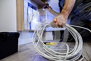 Close up shot of hand of aged electrician, repairman in uniform working, fixing, installing an ethernet cable in fuse