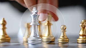 Close up shot hand of business woman moving golden chess to defeat a silver king chess on white and black chess board for business