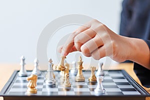 Close up shot hand of business woman moving golden chess to defeat a silver king chess on white and black chess board for