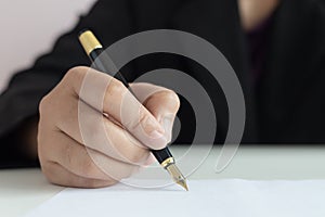 Close up shot hand of business woman using the pen to write on the white paper select focus shallow depth of field