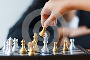 Close up shot hand of child moving golden chess to defeat and kill silver king chess on white and black chess board for business