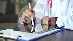 Close up shot hand of doctors with stethoscope are using tablets to write treatment reports or view patient information. New