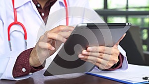 Close up shot hand of doctors with stethoscope are using tablets to write treatment reports or view patient information. New