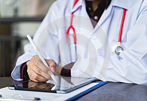Close up shot hand of Doctors with stethoscope are using tablets to write treatment reports or view patient information. New