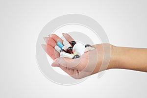 Close-up shot of a hand holding color pills on white background