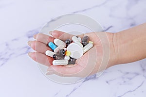 Close-up shot of a hand holding color pills on white background