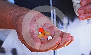 Close up shot of a hand holding several medicines.