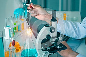 Close-up shot of the hand of a male scientist is experimenting with tube and microscope.