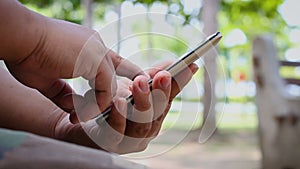 Close up shot hand of man using mobile smart phone in nature public park with ambient sound