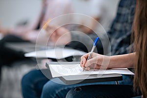 A close-up shot of a hand and a sheet of paper on which a student takes notes during a lecture at the university